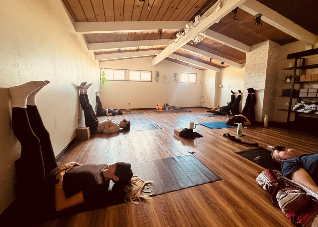 Corporate Yoga class, students are on their mats in Shavasana with legs up the wall