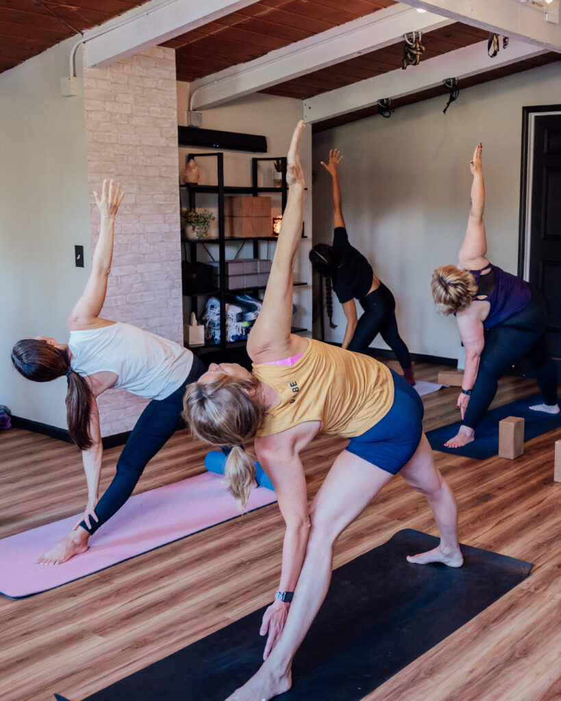 Group participating in a yoga session at VIBE, on mats in triangle pose.